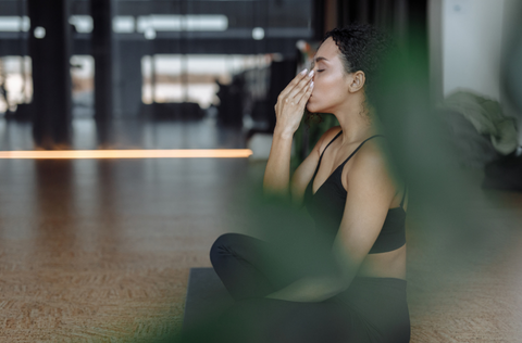 A woman in a yoga position with her hand over her mouth.png