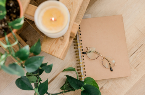 Candle, plant and glasses on a spiral notebook