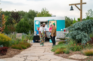 two men stand in front of a turquoise food truck
