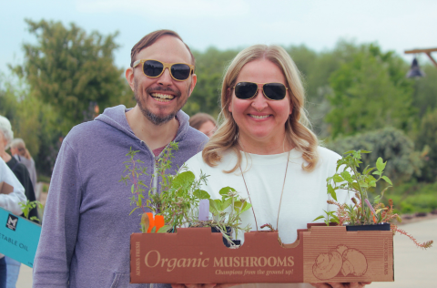 Man and Woman smiling holding a box of plants